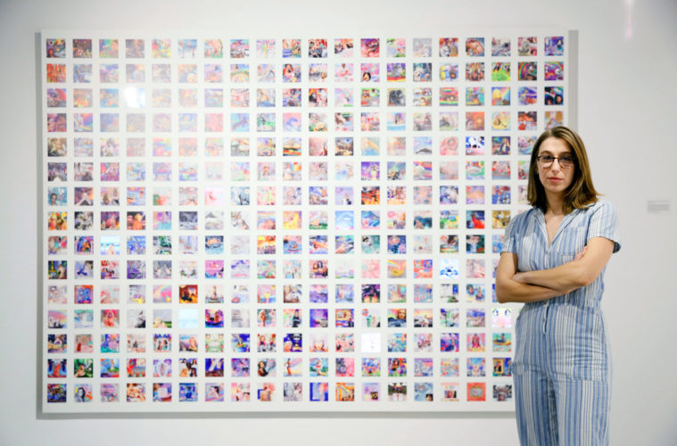 Casey Kauffmann in front of her piece IRL at the USC Roski Open Studios 2020 IRL 2019 291 iPhone collages printed on pvc with 9 GIFs playing on mini iPads 8 x 11 ft