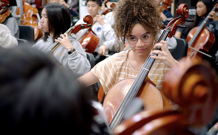 Student Jana plays the cello in the Sinfonia orchestra an ensemble for 8th grade musicians in a still from ARTBOUND Arts Education