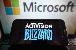 Activision Blizzard logo is displayed on a smartphone with Microsoft logo on the background.